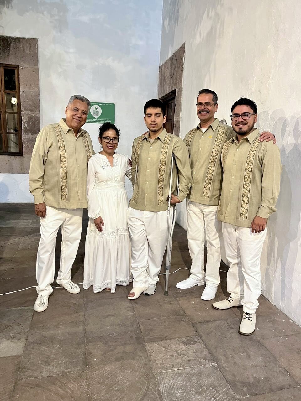 Grupo del elenco posando en backstage, uno con muletas por una lesión